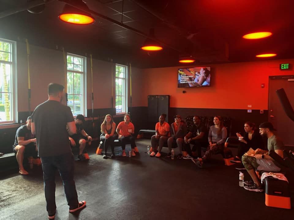 A facilitator addressing a seated group in a fitness studio