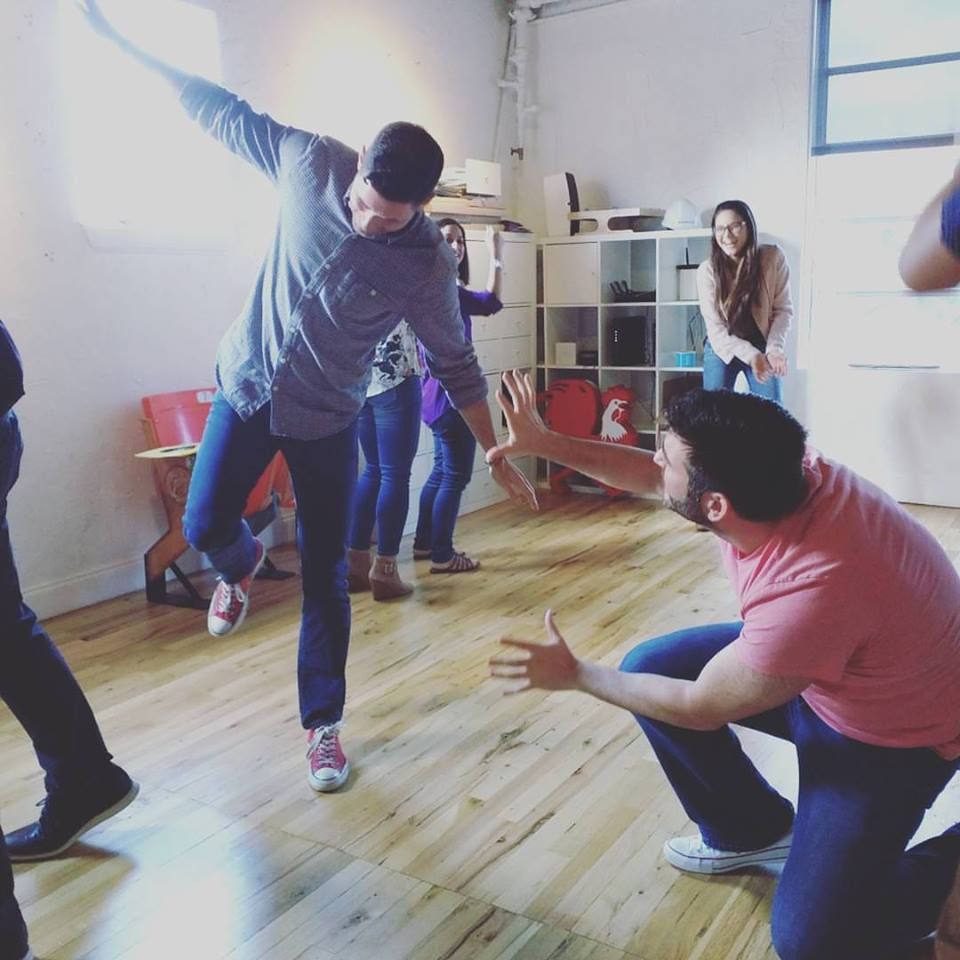 Two participants acting out a scene while coworkers laugh