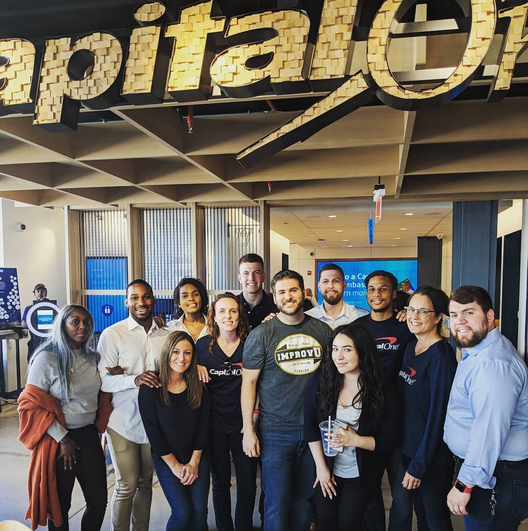 A company team posing with an Improv U facilitator in their office